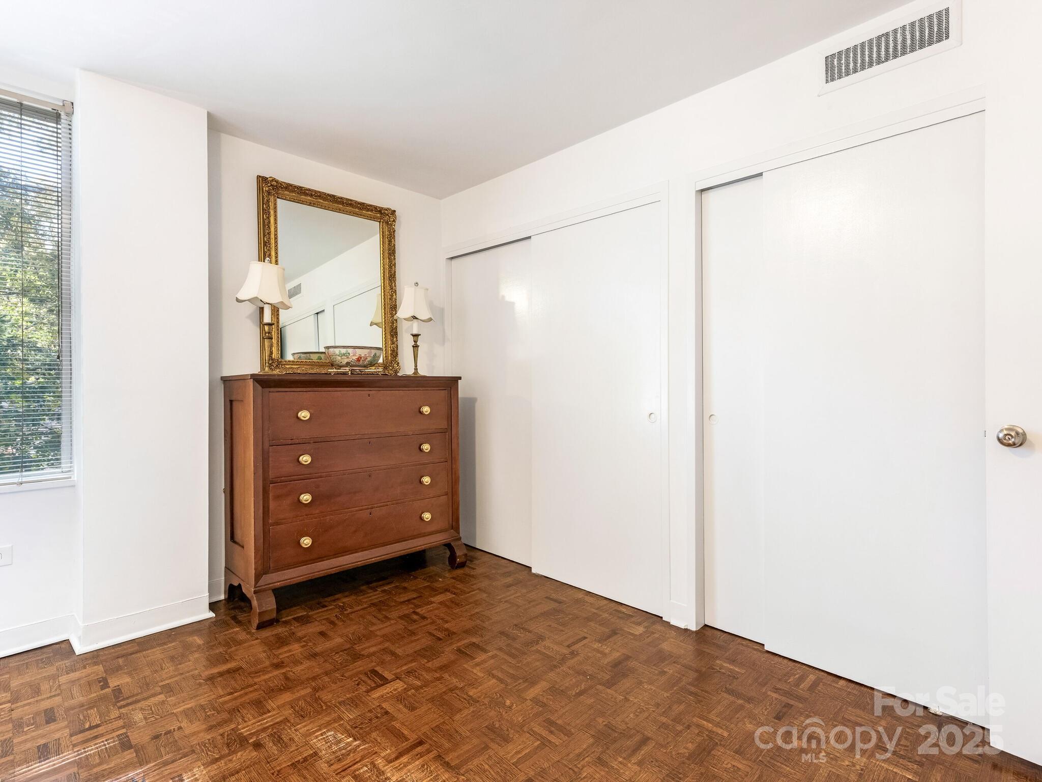 1300 Queens Road, Unit 401 Charlotte, NC 28207 - Photo 8 of 21 a view of a bedroom with a dresser and mirror