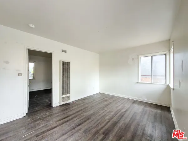 an empty room with wooden floor and bathroom