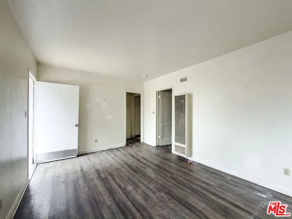 an empty room with wooden floor & closet and windows