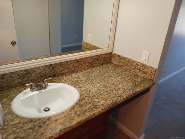a bathroom with a granite countertop toilet sink and mirror