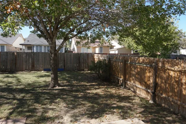a view of a backyard with large trees and wooden fence