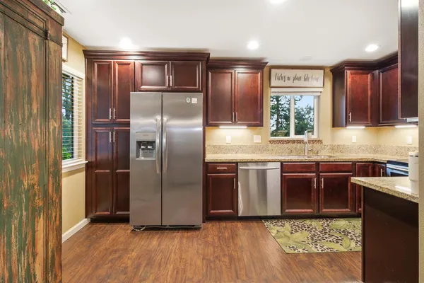 a kitchen with stainless steel appliances granite countertop a refrigerator a stove a sink and a microwave