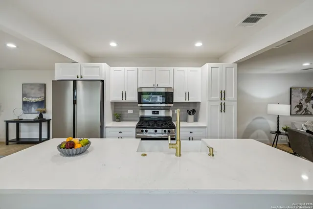 a kitchen with stainless steel appliances a refrigerator a stove a microwave a dining table and chairs