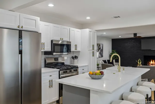 a kitchen with stainless steel appliances a refrigerator a sink a stove and cabinets