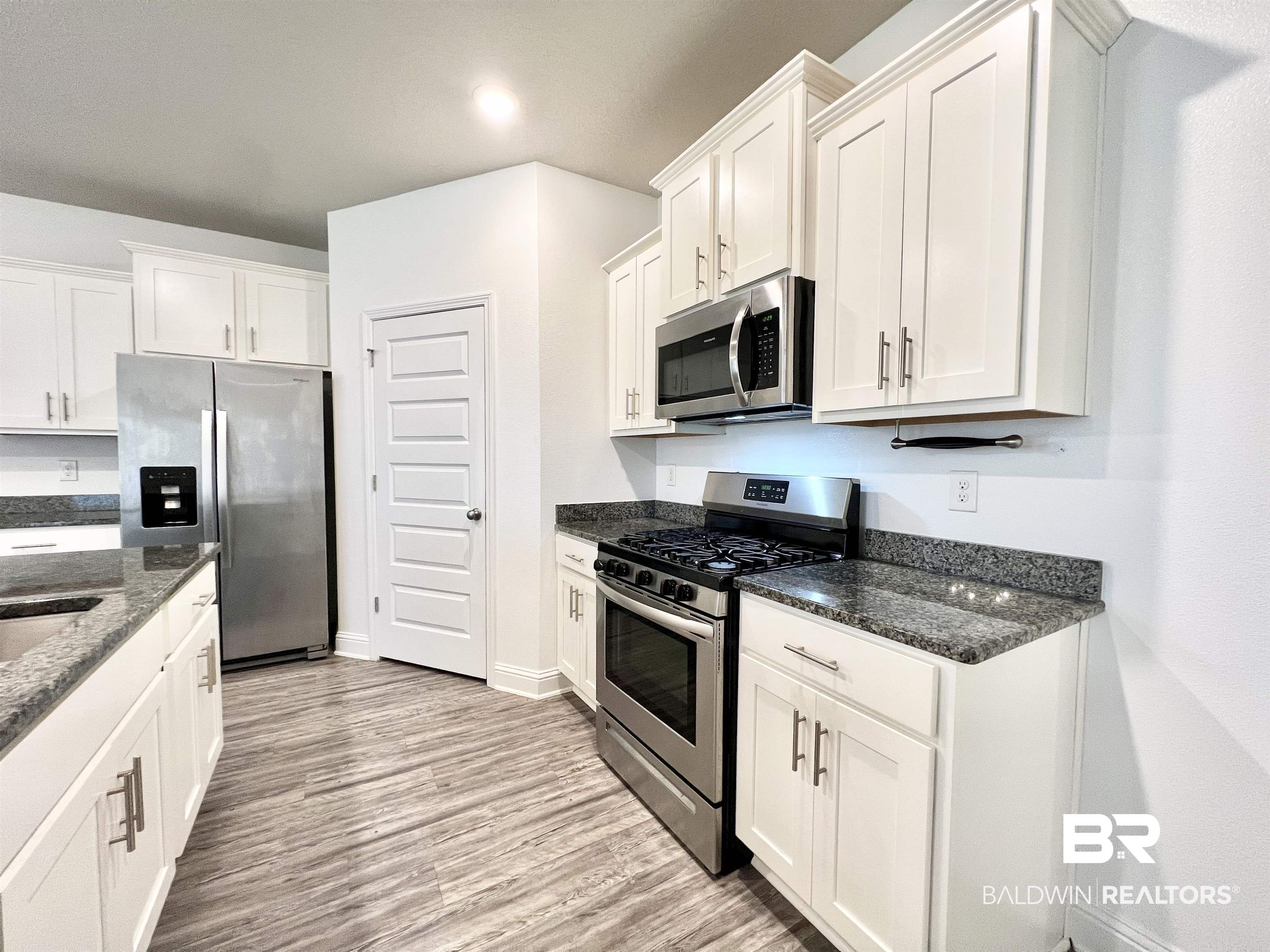 24785 Slater Mill Road Daphne, AL 36526 - Photo 6 of 46 Kitchen featuring dark stone countertops, appliances with stainless steel finishes, light hardwood / wood-style flooring, and white cabinets