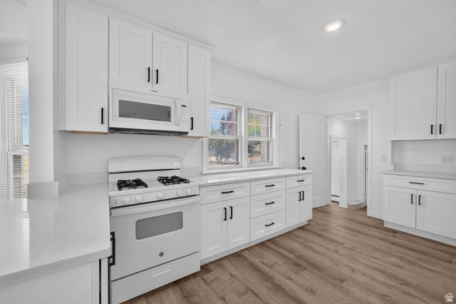 220 East Greenwood Avenue Midvale, UT 84047 - Photo 8 of 46 Modern kitchen featuring white shaker cabinetry, quartz countertops, stainless steel appliances, and wood-finish flooring