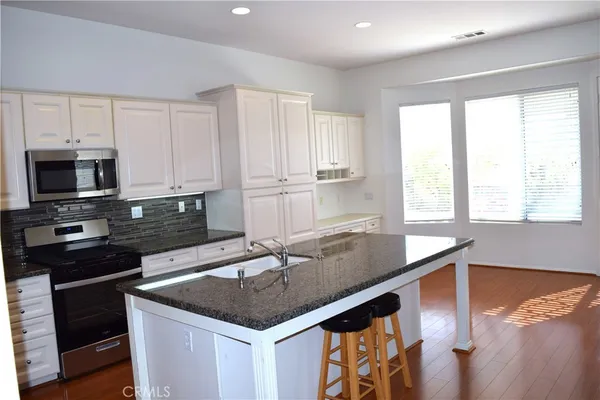 a kitchen with stainless steel appliances granite countertop a sink a stove and a microwave