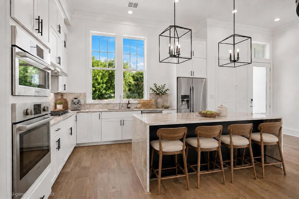 Contemporary kitchen featuring white shaker cabinetry with brushed nickel hardware, stainless steel appliances including a built-in microwave and refrigerator with ice dispenser, quartz waterfall-edge island countertop, wood-finish flooring, and geometric pendant lighting fixtures suspended above the island seating area