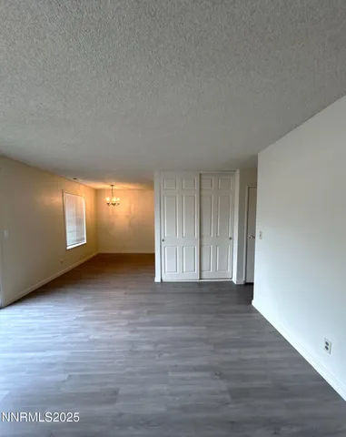 a view of an empty room with wooden floor and windows