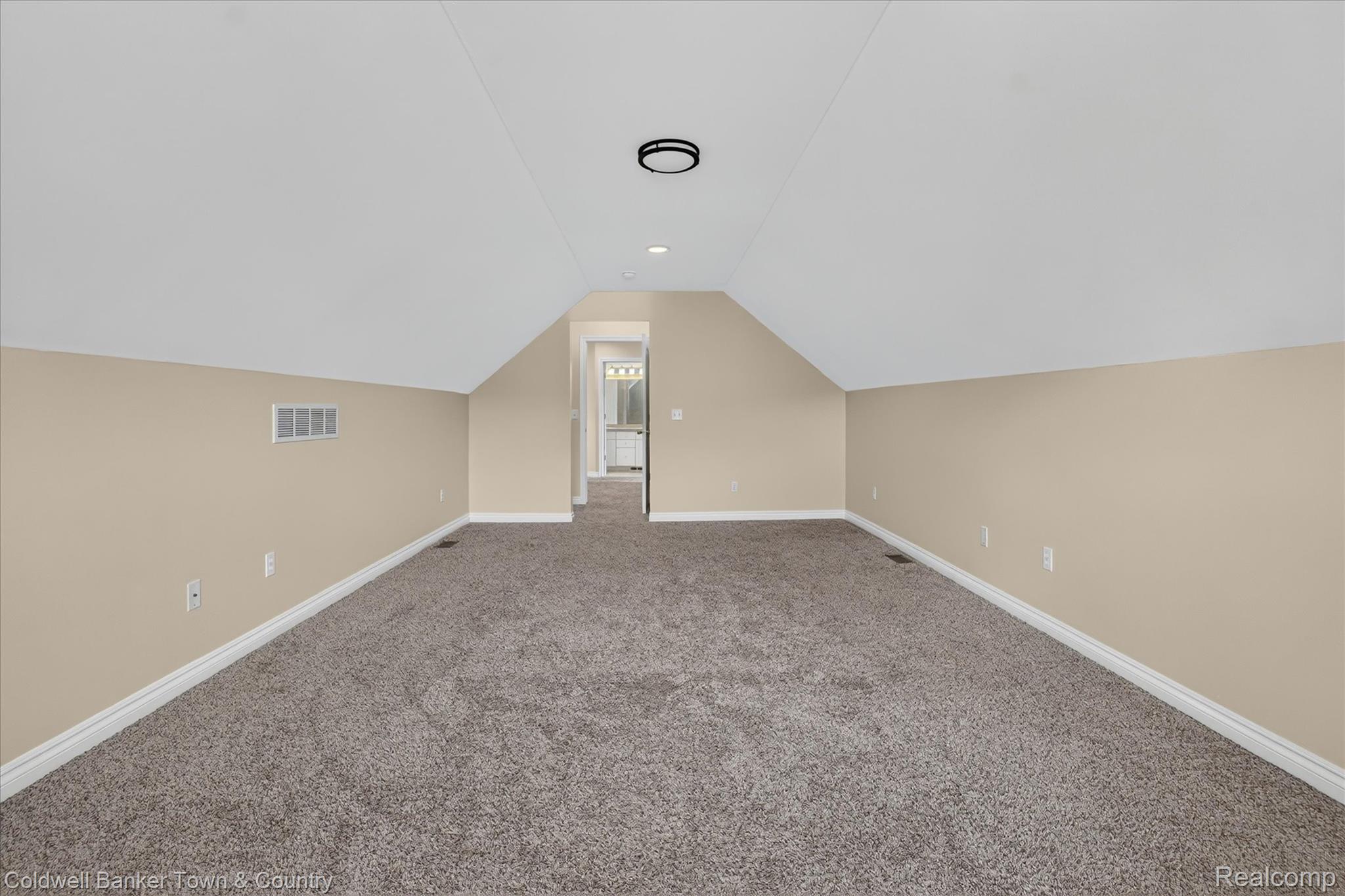 1725 Town Commons Drive Howell, MI 48855 - Photo 41 of 53 Expansive carpeted room featuring vaulted ceilings, light tan wall paint, white baseboards, and a circular flush-mount ceiling light