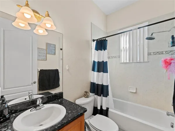 a bathroom with a granite countertop sink mirror toilet and bathtub