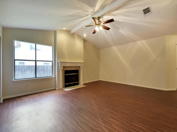 an empty room with wooden floor fireplace and windows