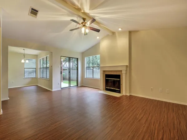 an empty room with wooden floor fireplace and windows