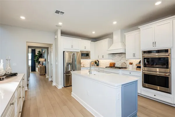 a kitchen with stainless steel appliances granite countertop a stove top oven a refrigerator a sink and dishwasher with wooden floor