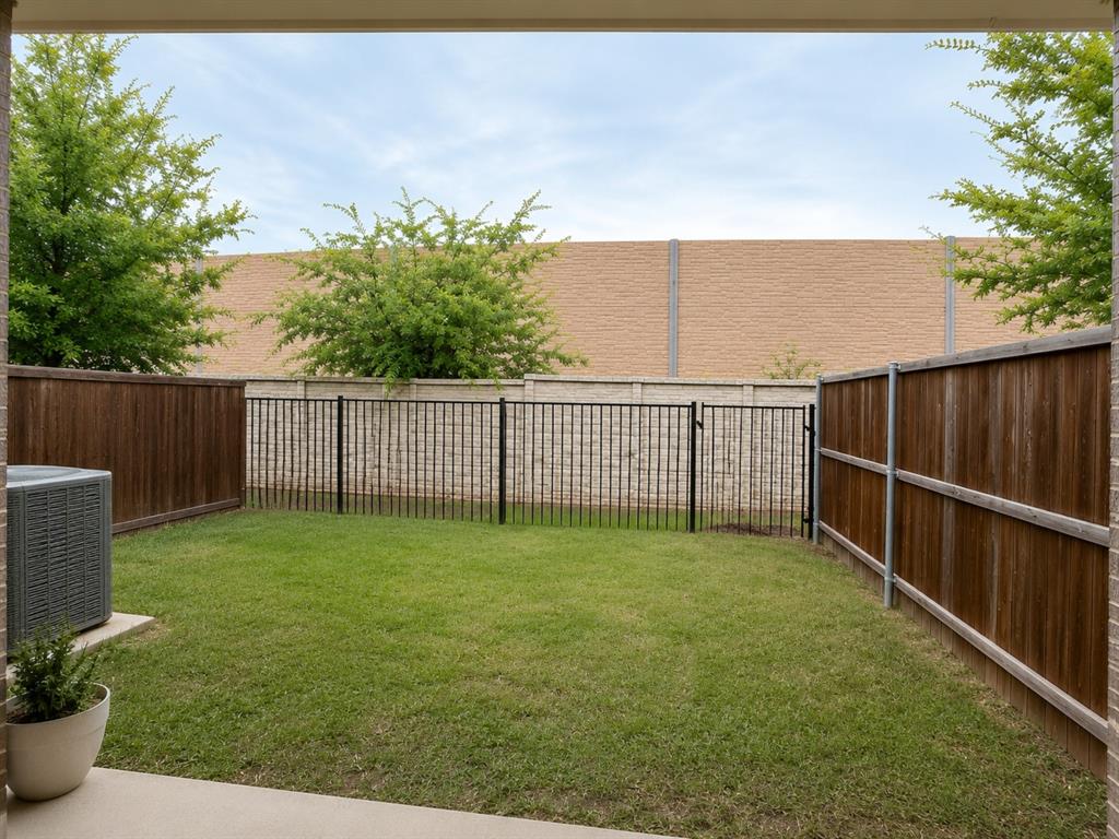 8235 Snapdragon Way Dallas, TX 75252 - Photo 23 of 29 Private outdoor space featuring a manicured lawn, wood fencing, and a black wrought iron fence with gate