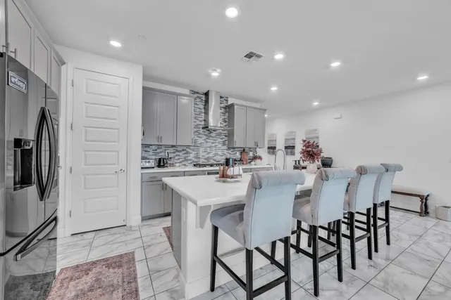 a kitchen with stainless steel appliances kitchen island granite countertop a dining table chairs sink and cabinets
