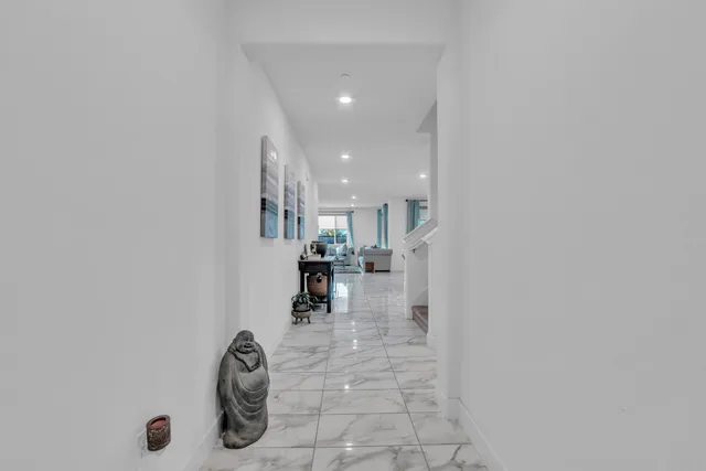 a view of a hallway with seating area and a bathroom