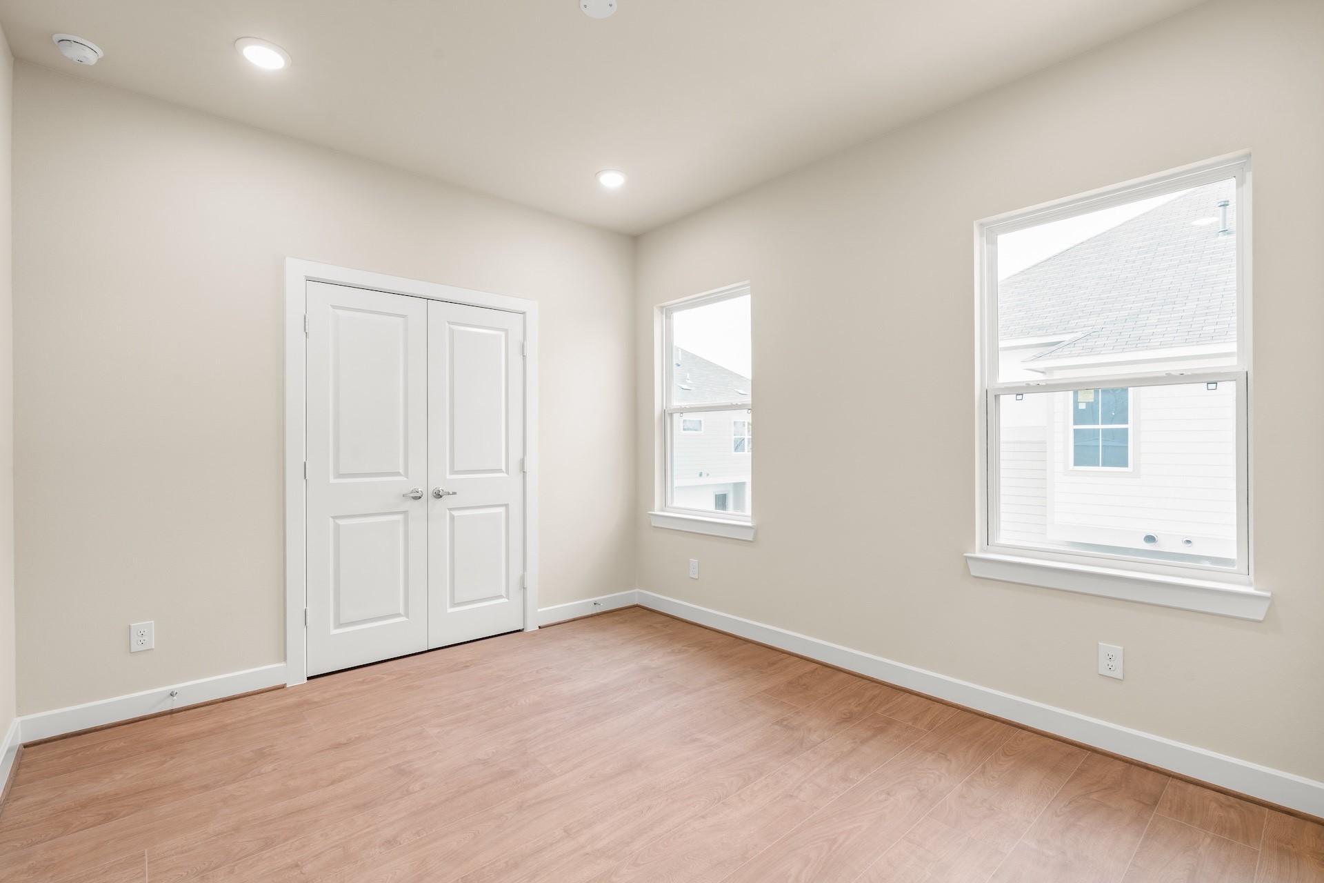 6521 Rena Street Houston, TX 77092 - Photo 18 of 24 Comfortable guest bedroom — double-door closet storage, dual sash windows streaming natural light, and warm wide-plank flooring throughout.