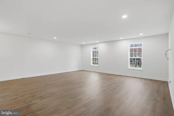 a view of an empty room with wooden floor and windows