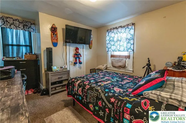 a bedroom with a bed and a flat tv screen on the dresser