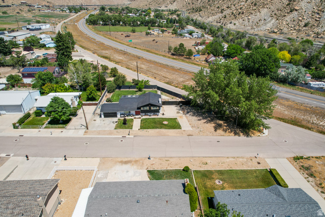 100 Third North Helper, UT 84526 - Photo 8 of 30 Aerial view showcasing a residential property with a dark-roofed home, an attached garage, and a landscaped front yard with green lawn