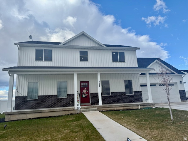Modern farmhouse style home featuring covered porch, a front yard, brick siding, concrete driveway, and an attached garage