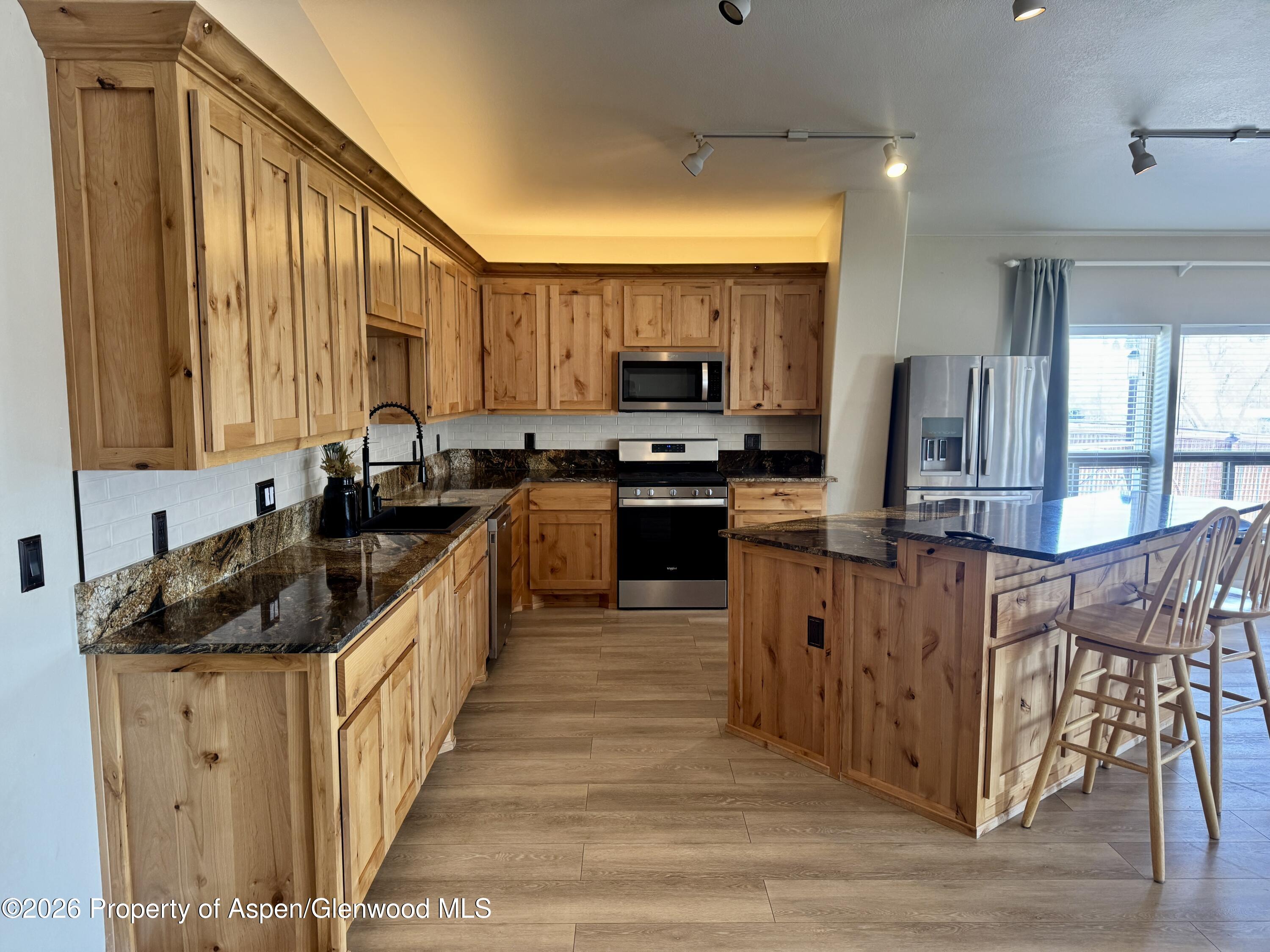 1287 Market Street Meeker, CO 81641 - Photo 2 of 42 a kitchen with stainless steel appliances granite countertop a stove top oven a sink dishwasher a refrigerator and a dining table with wooden floor
