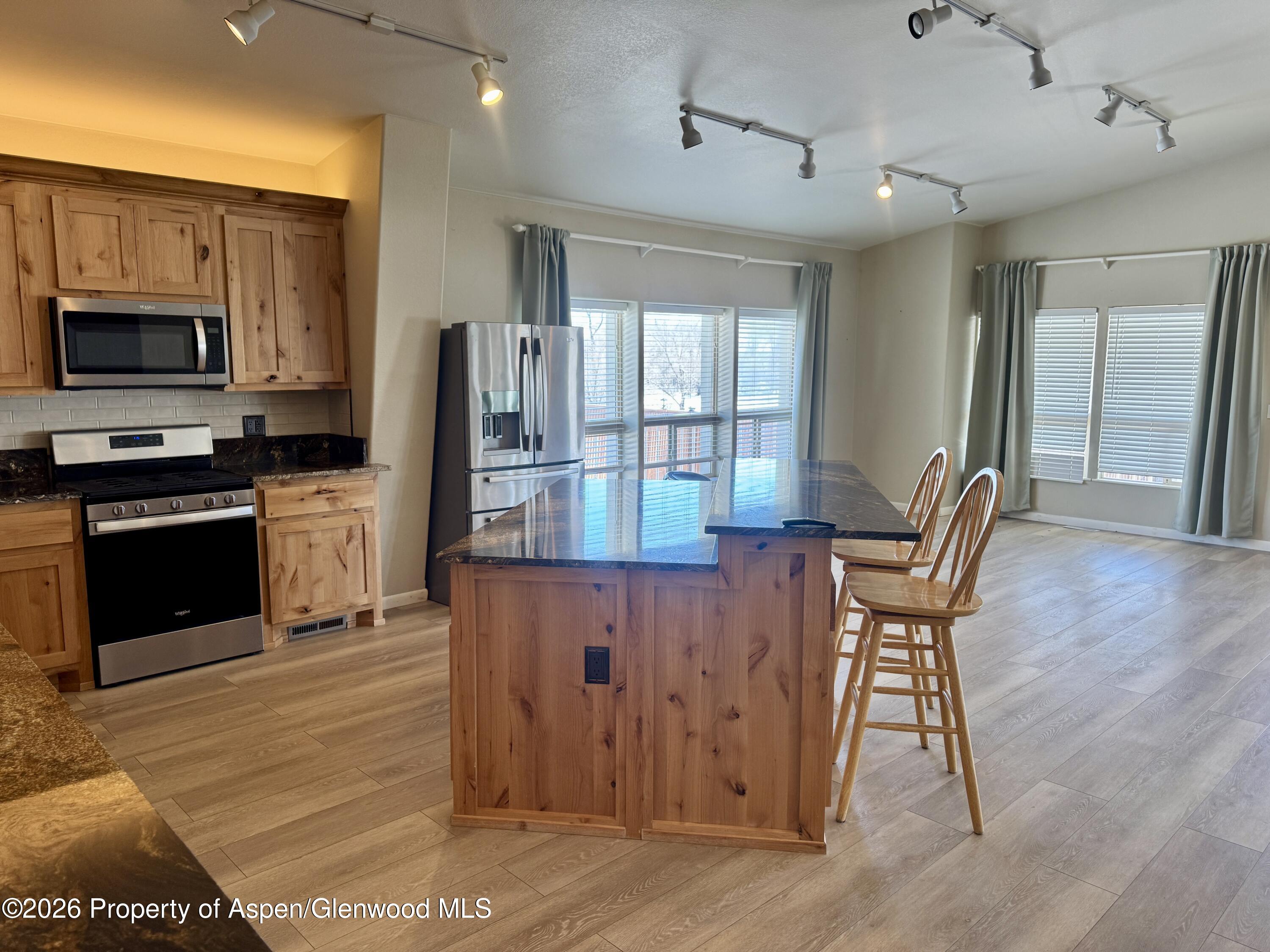 1287 Market Street Meeker, CO 81641 - Photo 4 of 42 a kitchen with stainless steel appliances granite countertop a stove top oven a sink dishwasher a dining table and chairs with wooden floor