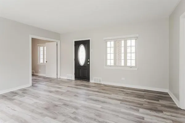 an empty room with wooden floor mirror and windows