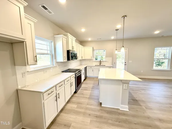 a large kitchen with stainless steel appliances kitchen island a large counter top and a wooden floors