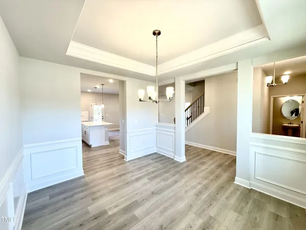 a view of a room with wooden floor kitchen view and a chandelier