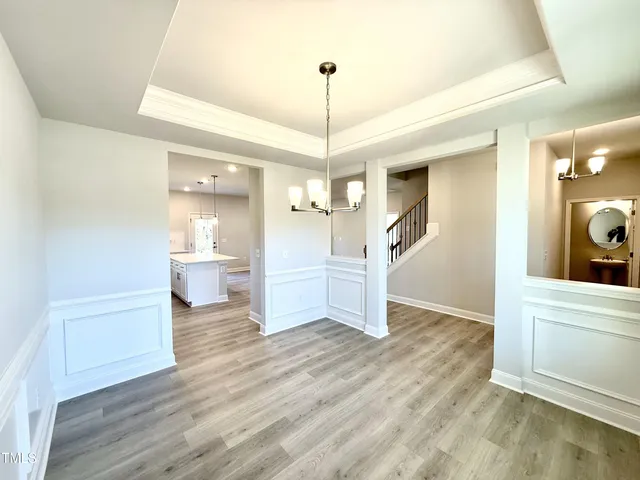 a view of a room with wooden floor kitchen view and a chandelier