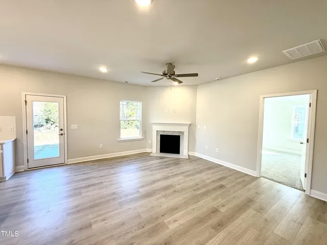 an empty room with wooden floor a fireplace and windows