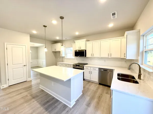 a large kitchen with kitchen island a sink a stove a center island and a window