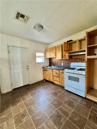 a kitchen with stainless steel appliances a stove a sink and white cabinets