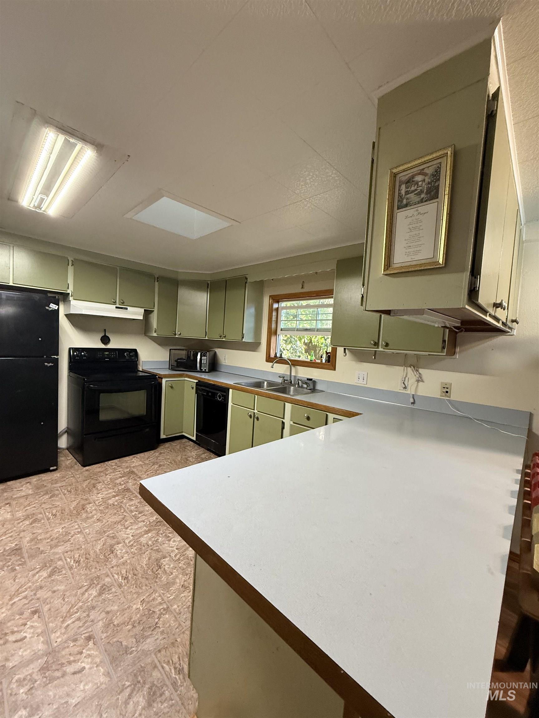 3210 Highway 162 Kamiah, ID 83536 - Photo 16 of 28 Kitchen with green cabinets, black appliances, light countertops, a peninsula, and under cabinet range hood