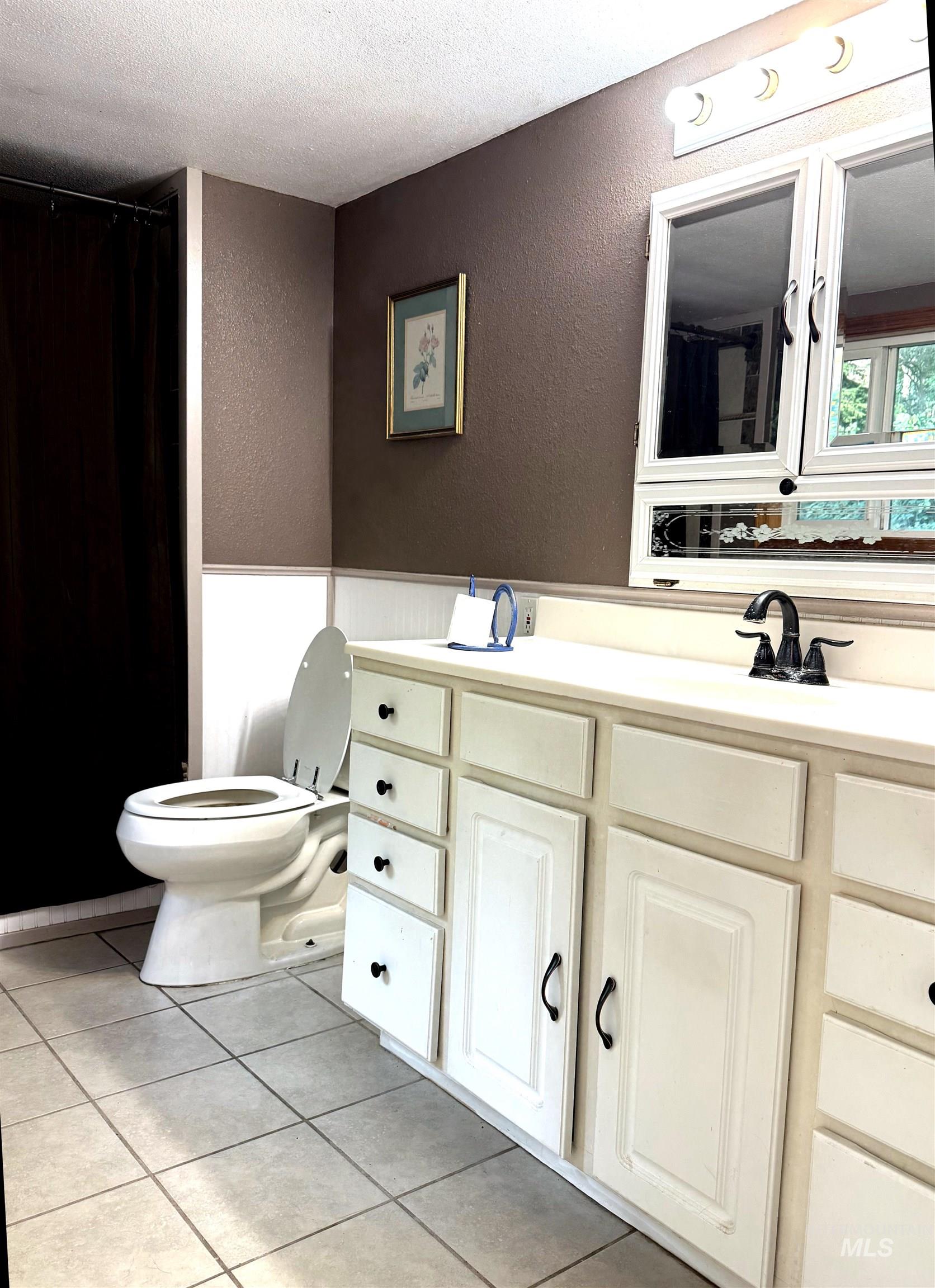 3210 Highway 162 Kamiah, ID 83536 - Photo 25 of 28 Full bath featuring a textured wall, vanity, light tile patterned floors, a textured ceiling, and curtained shower