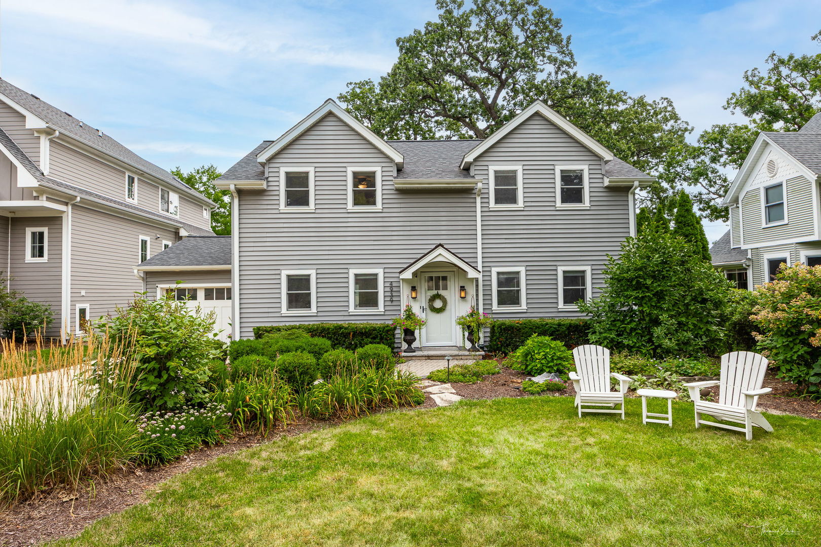 a front view of a house with a garden and chairs