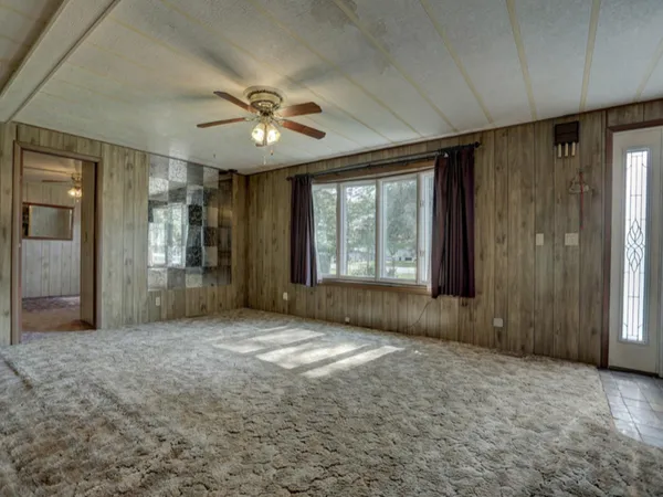 an empty room with windows and a ceiling fan