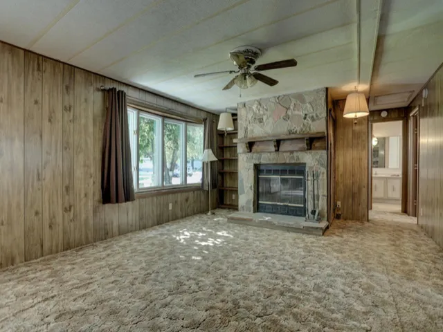a view of a livingroom with a fireplace a ceiling fan and window