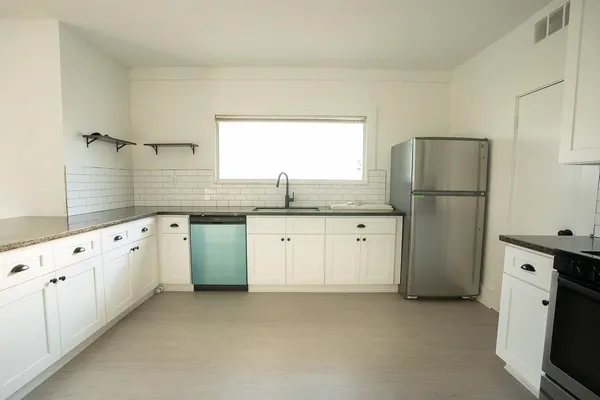 a kitchen with granite countertop white cabinets white appliances and sink