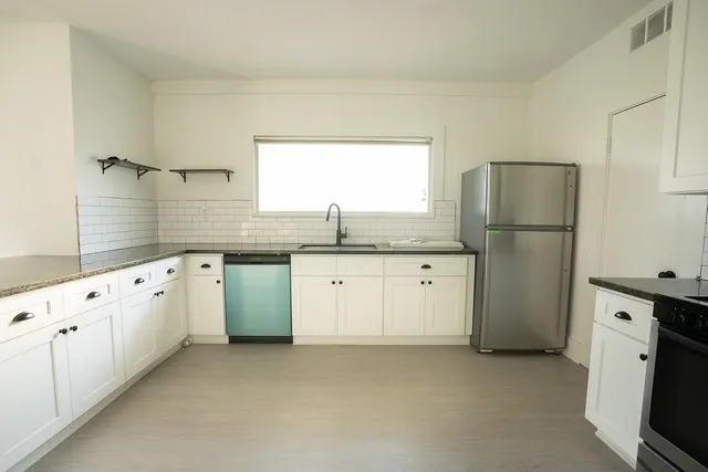 a kitchen with granite countertop white cabinets white appliances and sink