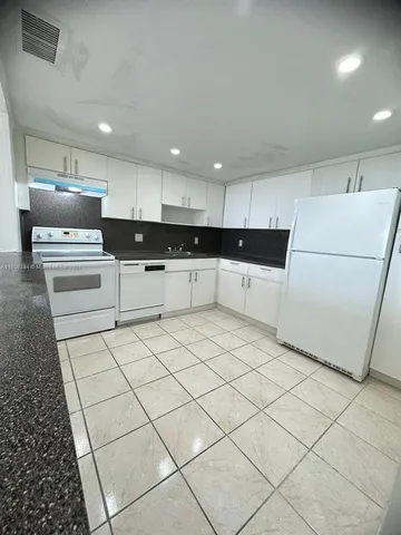 a large kitchen with kitchen island a sink a center island stainless steel appliances and a counter top space