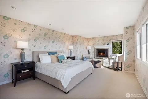 a bedroom with a bed a couch and a fireplace with wooden floor