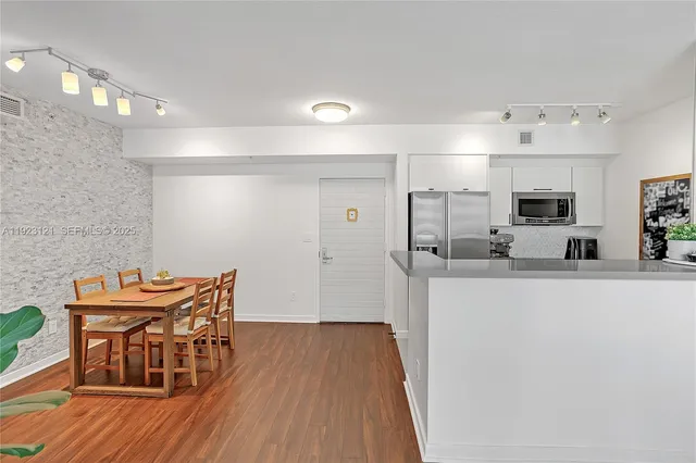 a kitchen with stainless steel appliances wooden floor dining table and chairs