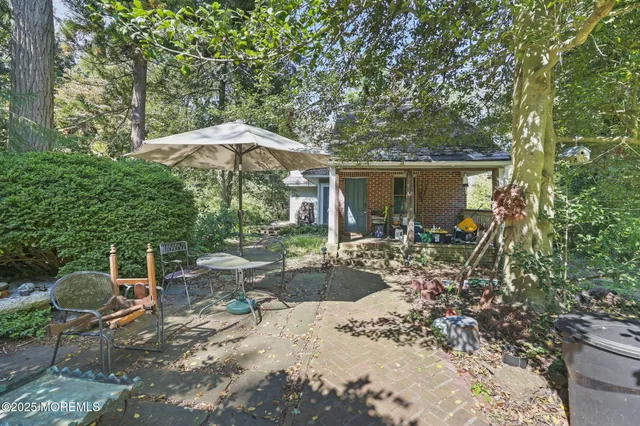 a backyard of a house with table and chairs under an umbrella