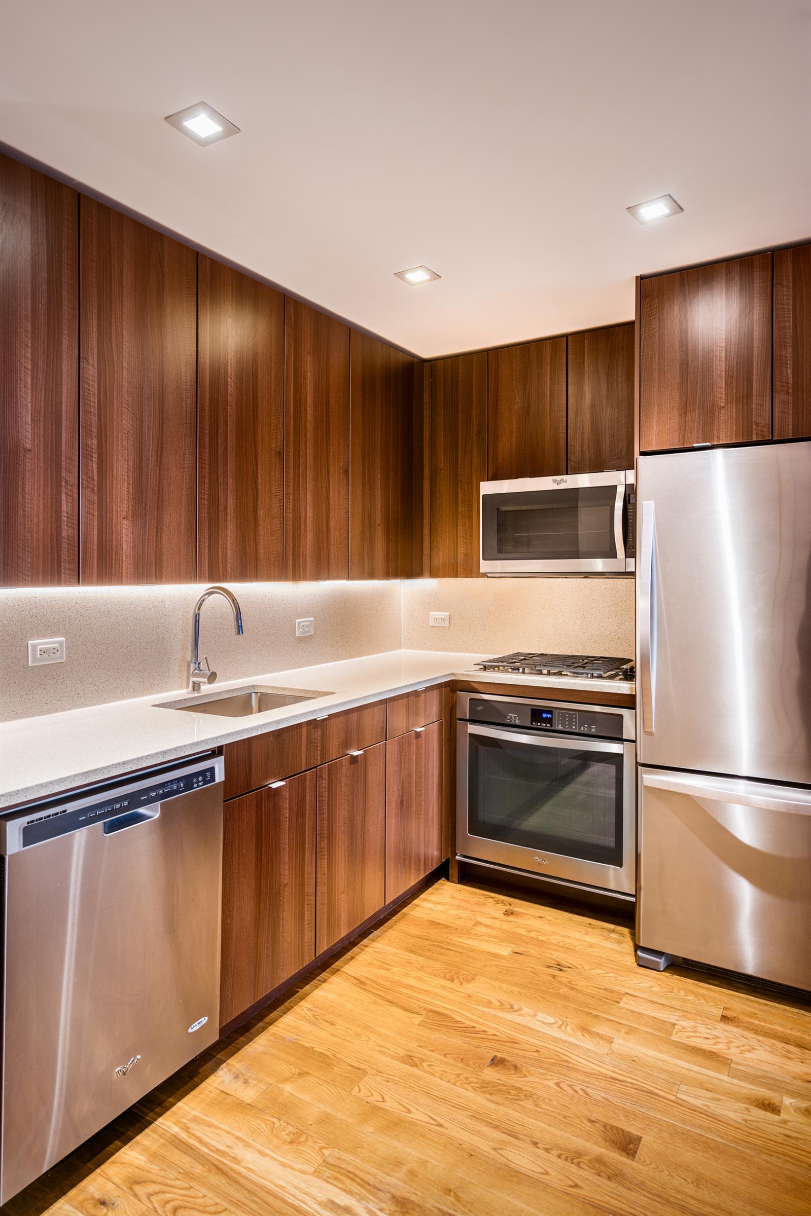 a kitchen with granite countertop stainless steel appliances wooden cabinets a sink and a refrigerator