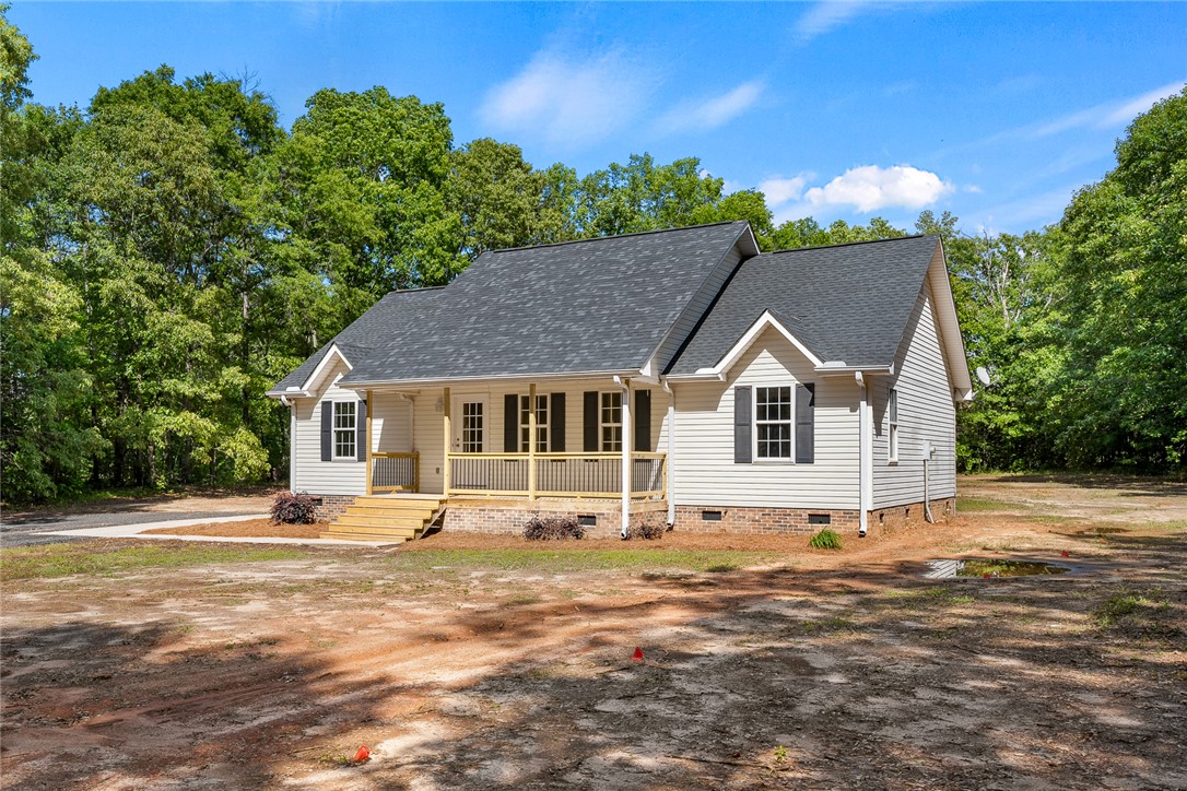 131 Lockaby Road Pelzer, SC 29669 - Photo 7 of 50 This newly constructed home features a welcoming front porch and classic architectural details, set against a backdrop of mature trees.