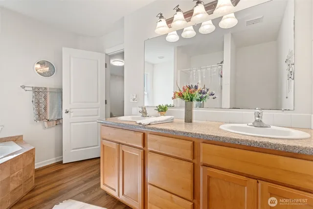 a bathroom with a granite countertop double vanity sink a mirror a vanity and a bathtub