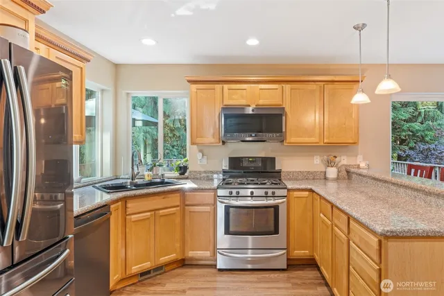 a kitchen with stainless steel appliances granite countertop a stove a sink and a refrigerator